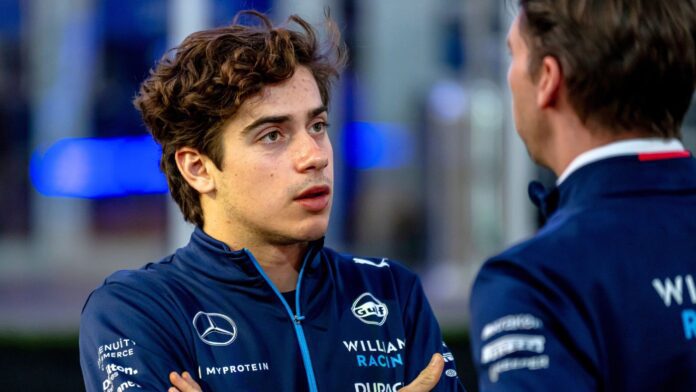 Franco Colapinto in Williams Racing attire, engaging in a focused conversation with James Vowles during an F1 weekend.